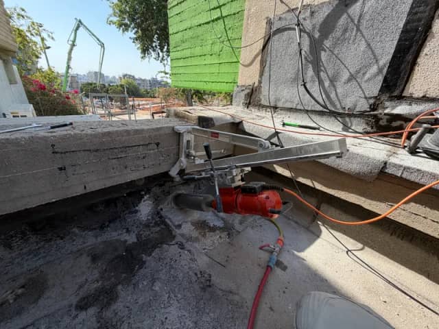 ניסור רצפת בטון באתר בנייה עם משאבת בטון ברקע